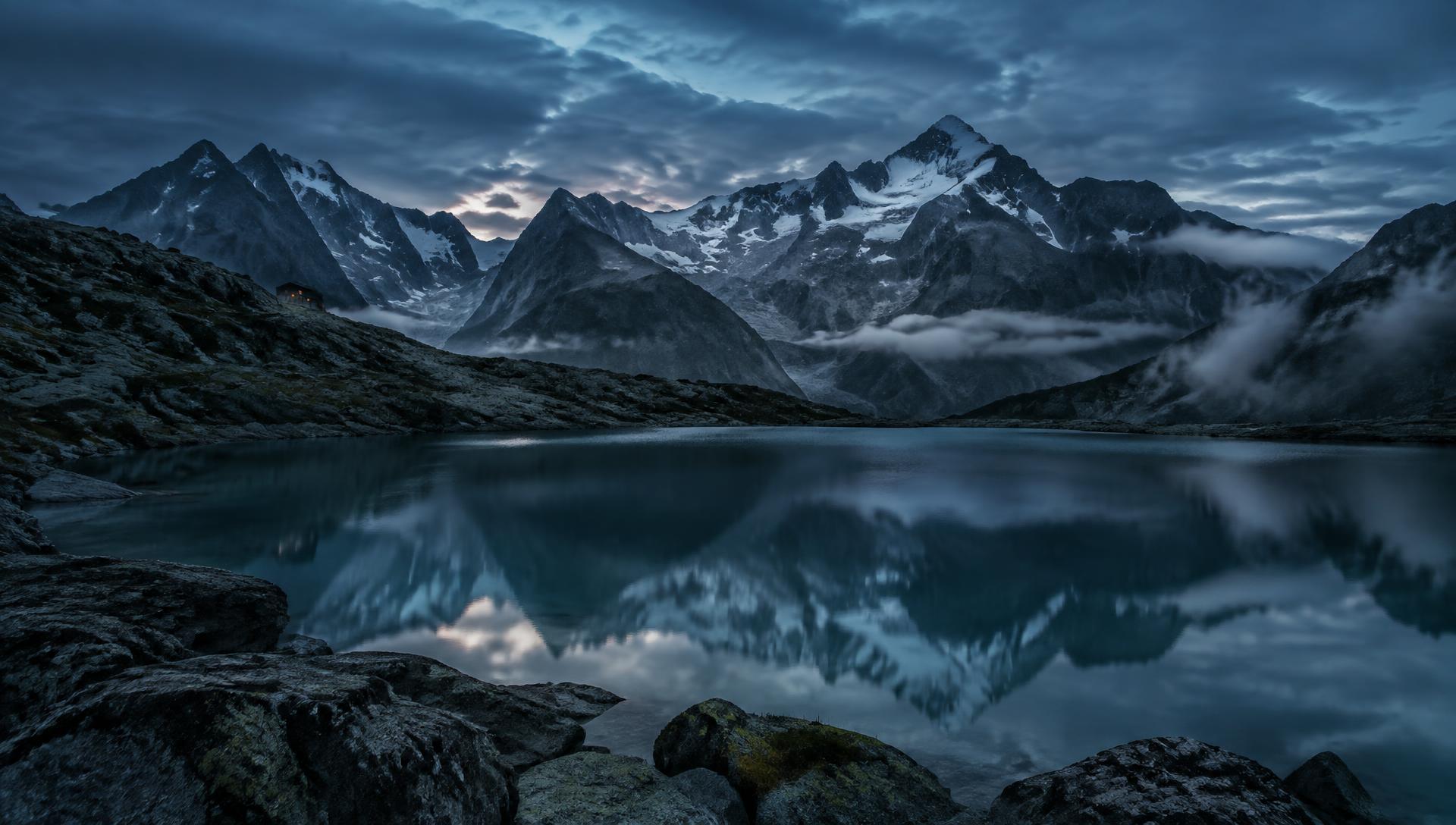 Alpine peaks reflected in a still mountain lake at dusk